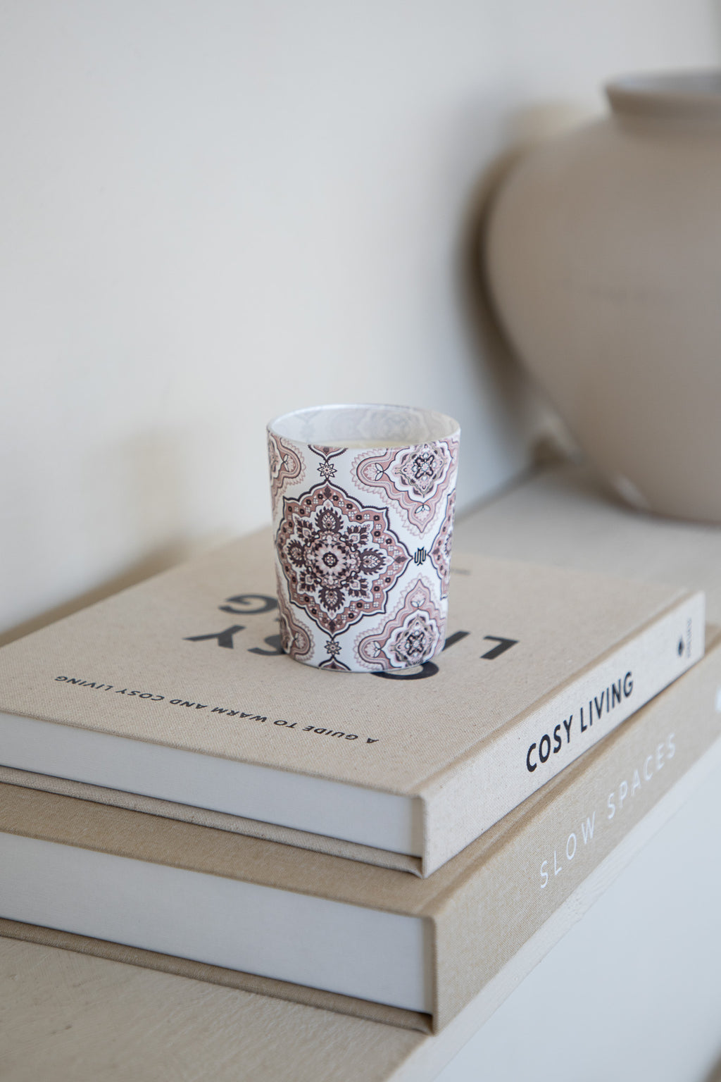 Soft beige luxury home fragrance candle with Arabesque design by Muriḥ displayed on books