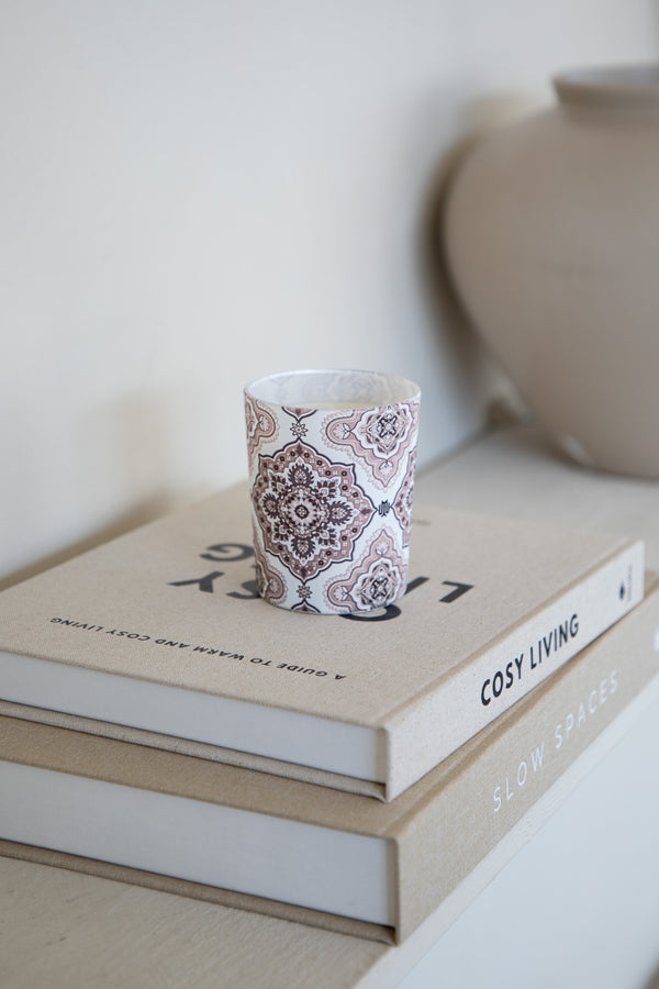 Soft beige luxury home fragrance candle with Arabesque design by Muriḥ displayed on books