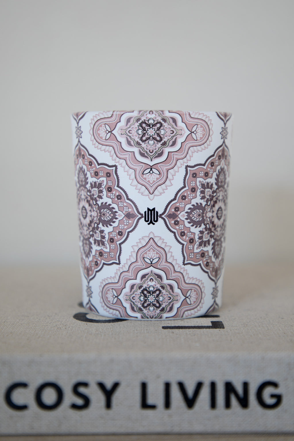 Close-up of a soft beige luxury candle with Arabesque design by Muriḥ displayed on books