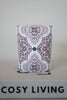 Close-up of a soft beige luxury candle with Arabesque design by Muriḥ displayed on books