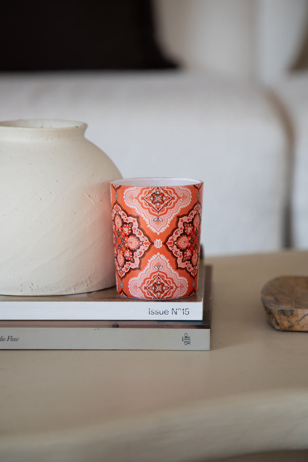 orange patterned luxury candle by murih displayed on books in a refined interior setting