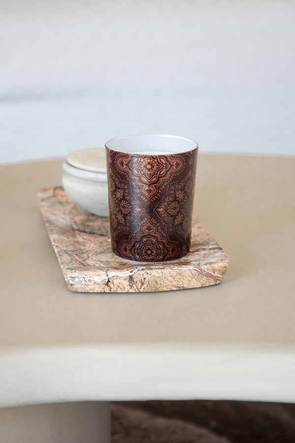 brown luxury candle with intricate Arabesque pattern by Muriḥ styled on a marble tray