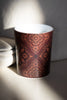 Close-up of a deep brown luxury candle with intricate Arabesque pattern by Muriḥ in dramatic lighting